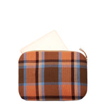 Hand woven artisan Elenita Laptop case in Brickstone color. The case is shown open with a computer sliding into it at a diagonal. The case has a plaid pattern with blue, orange, and brown colors. It has a leather zipper pull.