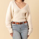 Hand woven artisan Celeste belt in Brickstone color. A model wears the belt and the photo is cropped to show the model's torso and waist wearing the belt. She is wearing a white sweater and light wash jeans.