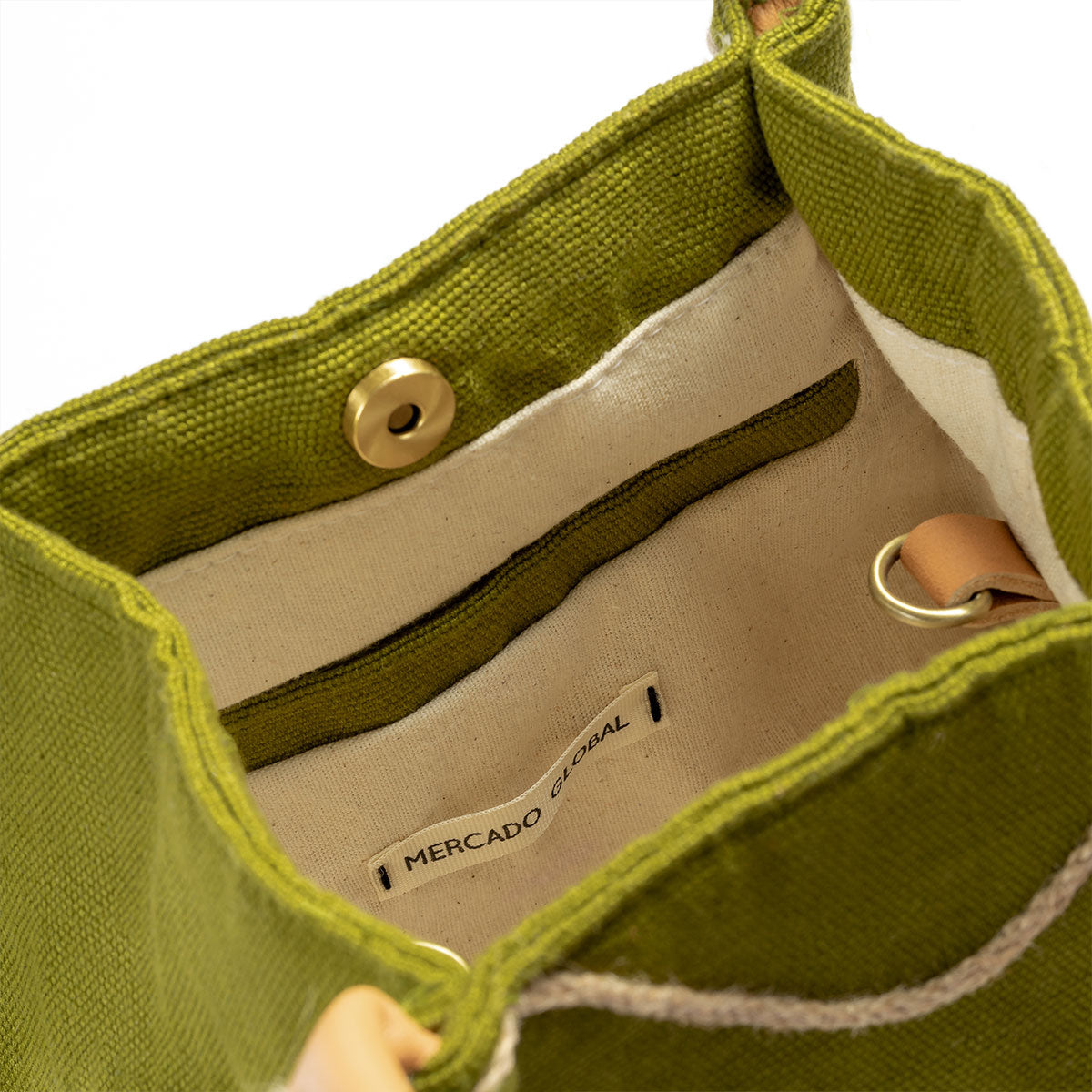 A zoomed in detail of the interior. The artisan hand woven Flora Petite Crossbody in Turf Moss. It has a beige lining and closes with magnetic clasps. It has leather loops for the detachable leather strap.