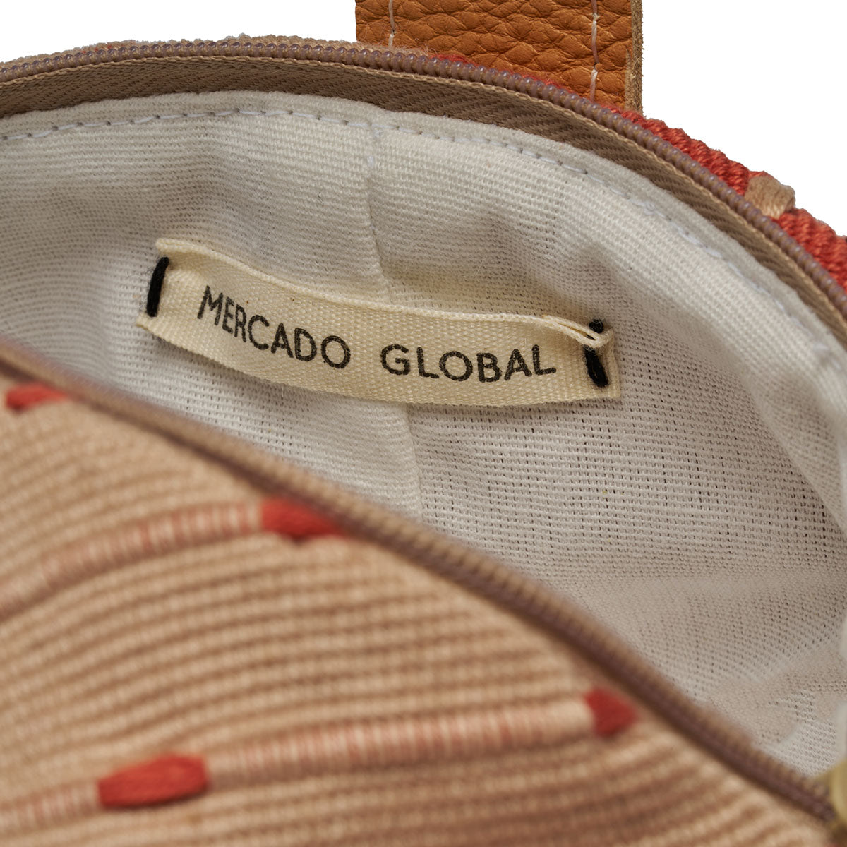 Interior unzipped view of the Dulce Wristlet in Desert Sands. It has a white cotton lining and Mercado Global label.