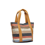 Side angle view of the Magali Tote in Blue Canyon. It has horizontal navy, orange, tan, beige, and light blue stripes. It has leather handles.
