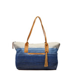 Front view of the Soledad Weekender in Ocean Breeze. It has a gradient white to dark blue pattern. It has leather handles, an exterior slip pocket, and a leather tassel.