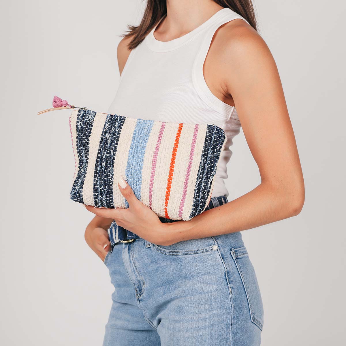 A model holds the artisan hand woven Cristina Cosmetic Pouch in Spring Sherbet pattern.