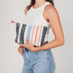 A model holds the artisan hand woven Cristina Cosmetic Pouch in Spring Sherbet pattern.