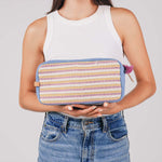 A model holds the hand woven artisan Edna Dopp Kit in Cream Soda in both hands.