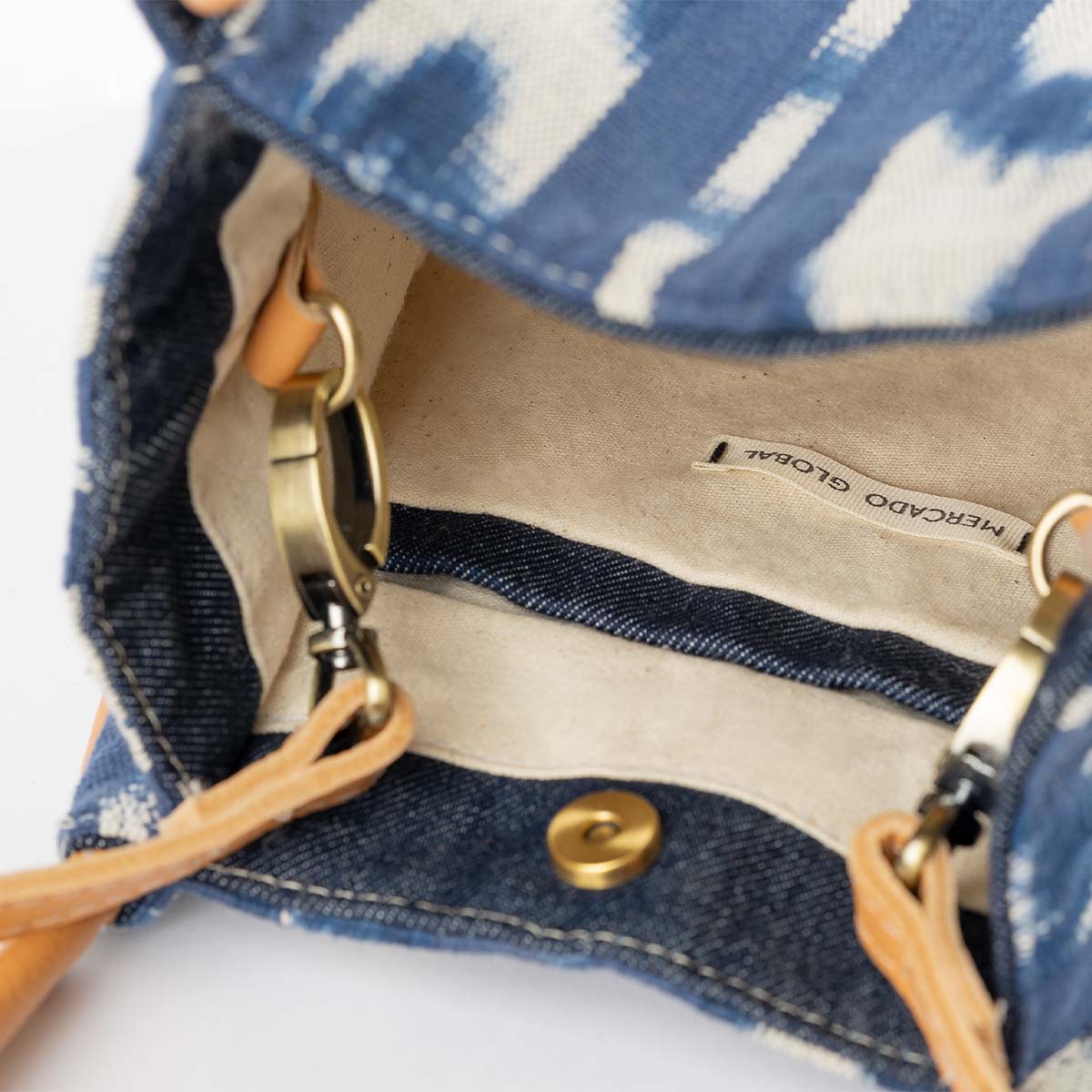 The interior of the hand woven artisan Flora Petite Crossbody in Atitlán Hills pattern. The interior has a beige solid lining and dark wash denim hem.