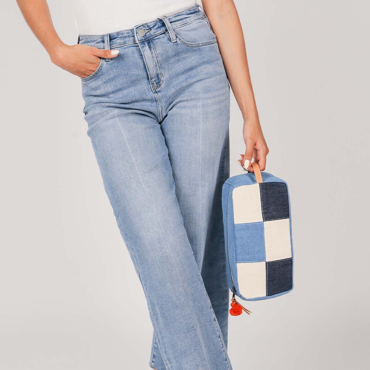 A model holds the leather handle of the hand woven artisan Edna Dopp Kit in 90s Denim