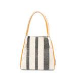 Back of the hand woven artisan Flora Petite Tote in Tourmaline pattern. It has vertical white and black stripes. It has a leather handle with white embroidery.