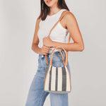 A model wears the hand woven artisan Flora Petite Tote in Tourmaline pattern.
