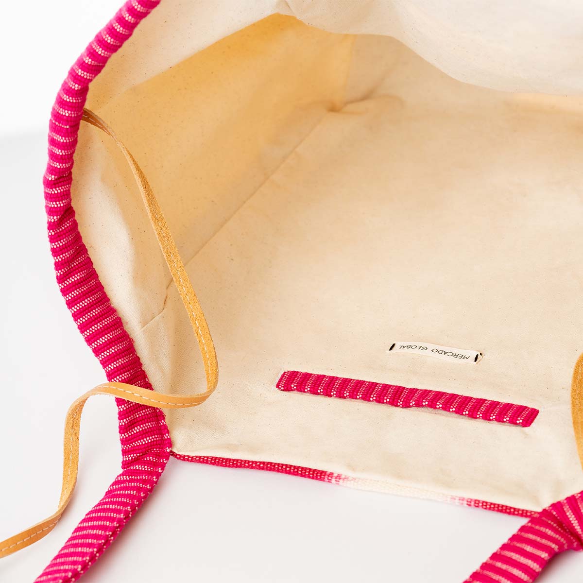 The interior of the hand woven artisan Rosa Tote in Raspberry Paleta pattern. The inside has a beige solid color. The interior pocket has a deep pink hem.