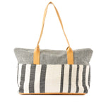 The back of the Soledad Weekender in Tourmaline pattern.It has grey and white vertical stripes and leather handles.