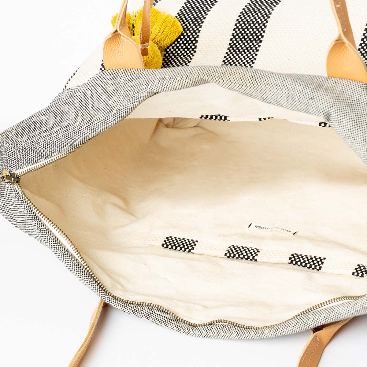 The interior of the Soledad Weekender in Tourmaline pattern. It has a beige solid color fabric and woven black and white cords sewn to either side.