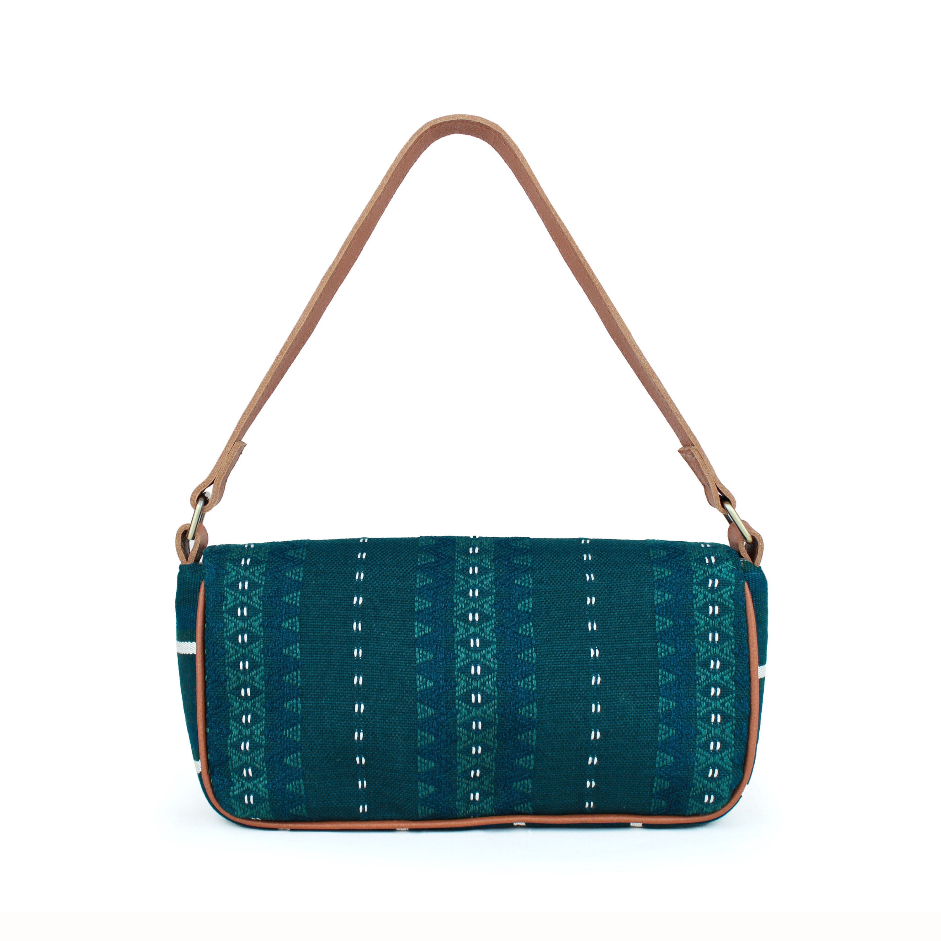 Back view of the Olivia Artisan Handwoven Deep Forest Shoulder Bag. It has a deep turquoise and white geometric pattern. It has a leather strap and leather piping. The bag has a short and long width shape.