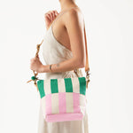 A model wears the hand woven artisan Mini Lidia Hobo bag. This bag has vertical thick green and pink stripes.