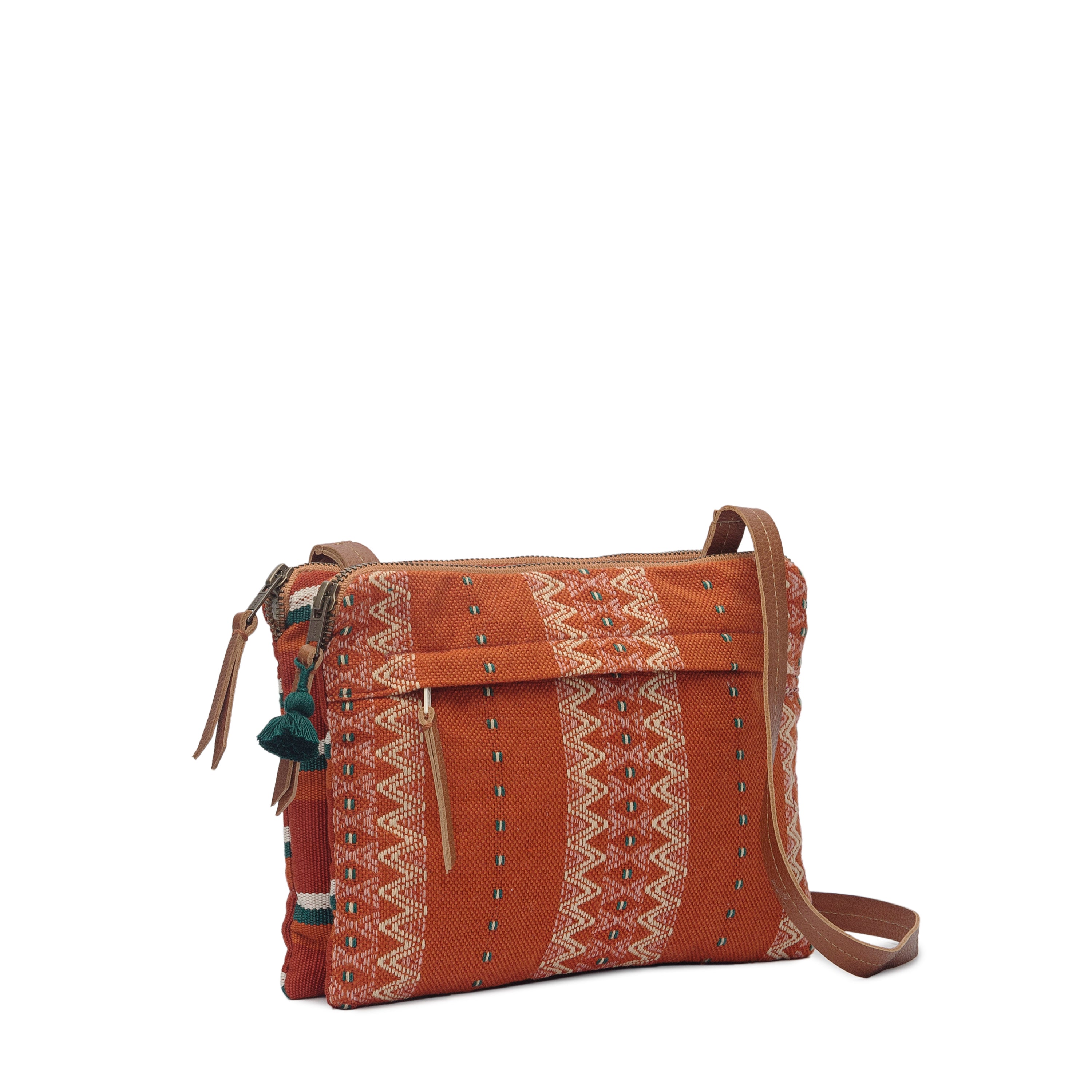 A side view of the hand woven artisan Miriam Crossbody in Ginger. It has a gusseted style on the sides. It has a leather strap and mini phthalo green tassel.