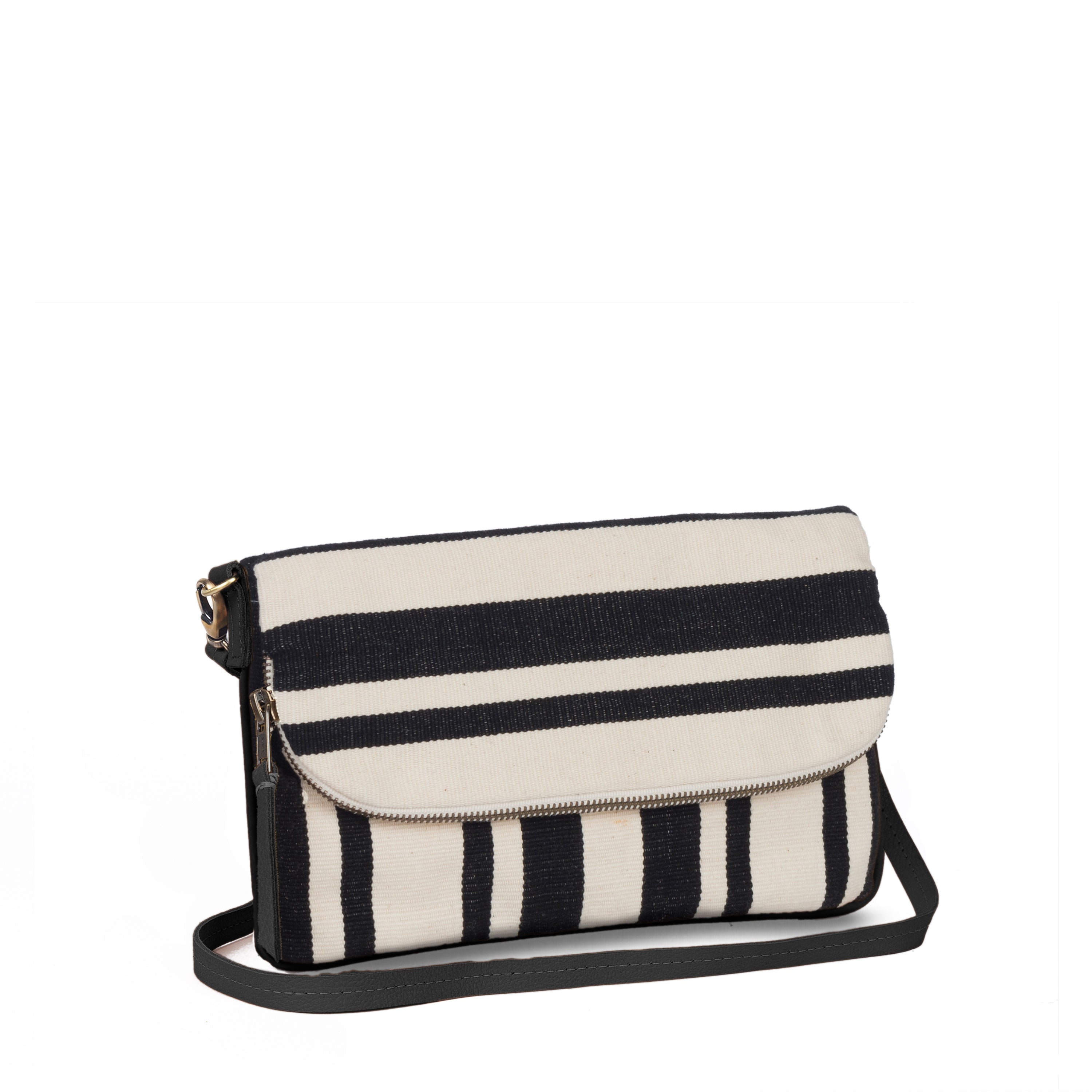 A side view of the hand woven artisan Paulina Crossbody-to-Clutch bag in Black Block Stripe. The bag has vertical and horizontal black and white stripes. It has a grey leather detachable strap.