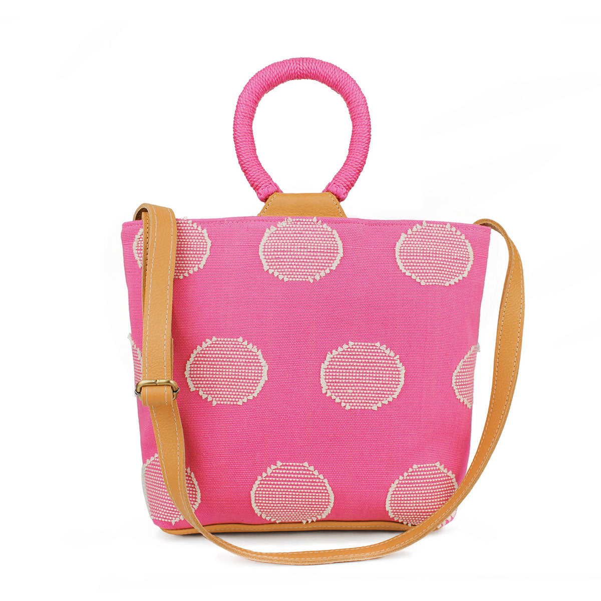 Artisan Dalila Handwoven Tote Sunset Pink. The tote has rounded handles coiled in pink thread. The Sunset Pink pattern has white circles over a pink background. It has an adjustable leather strap.