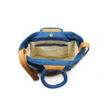 A top view of the interior of the hand woven artisan Dalila Midi Tote in Ocean Blue, showing an interior pocket with a blue hem. The lining is a beige fabric. The top hem has magnetic clasps.