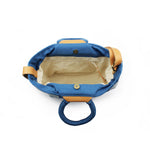 Another top view of the artisan hand woven Dalila Midi Tote in Ocean Blue. The side shows a pocket with a leather zipper pull. It has beige lining. The bag closes with magnetic clasps.