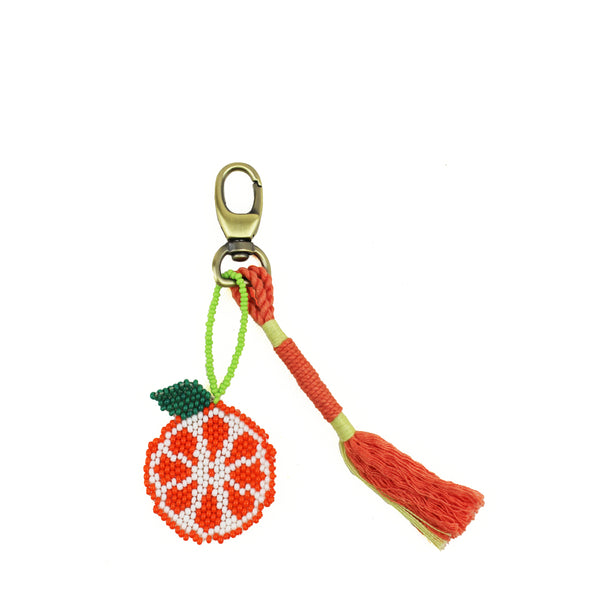 Hand woven artisan Go Bananas Keychain. It has a beaded orange graphic charm with an orange and green tassel. It is attached to a lobster claw metal clasp.