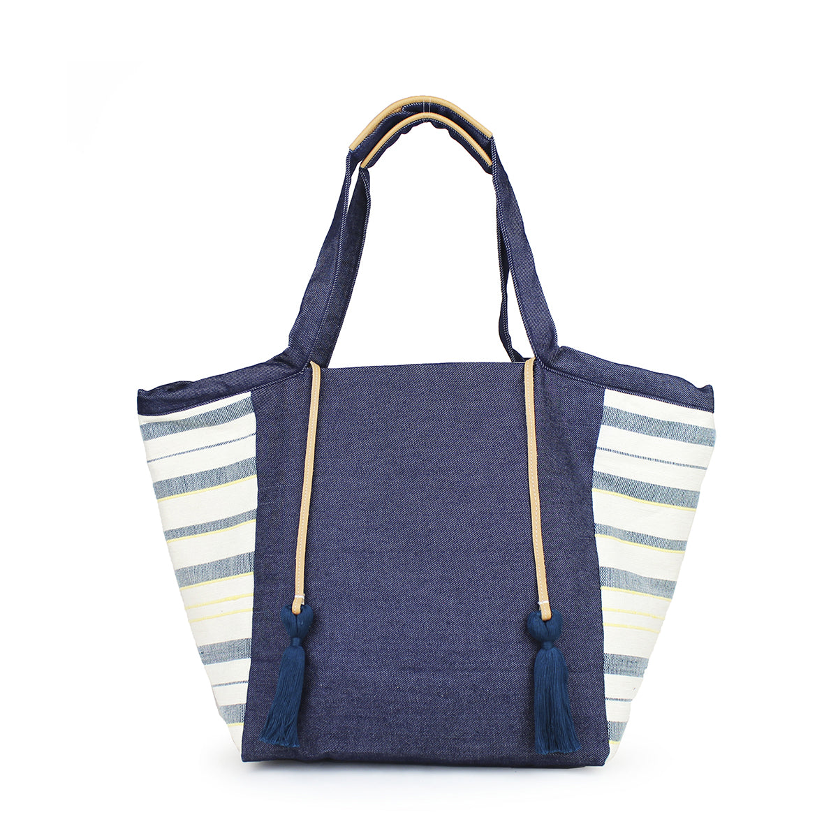 Artisan Rosa Handwoven Tote in Denim Ocean. The bag has a dark wash denim fabric with leather detailing on the handles. It has a light blue, yellow, and white horizontal striped fabric on the sides. It has two leather cords with dark blue tassels attached.