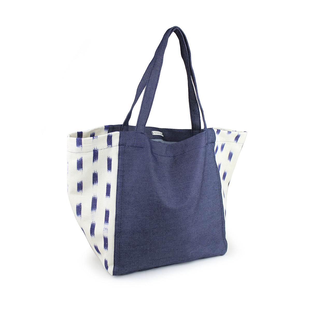A top left view of the artisan hand woven Blanca Tote in Denim Jaspe. The tote has a dark denim wash. The sides have an abstract blue square pattern over a white background.