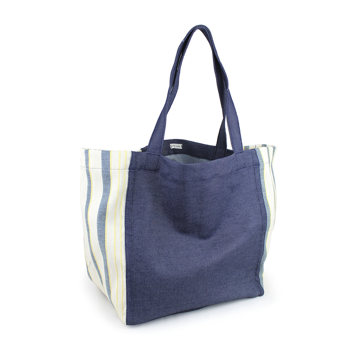 A left-sided angle of the hand woven artisan Blanca Tote in Denim Ocean pattern. The tote has a dark wash denim. The sides have a light blue, yellow, and white vertical striped fabric. 