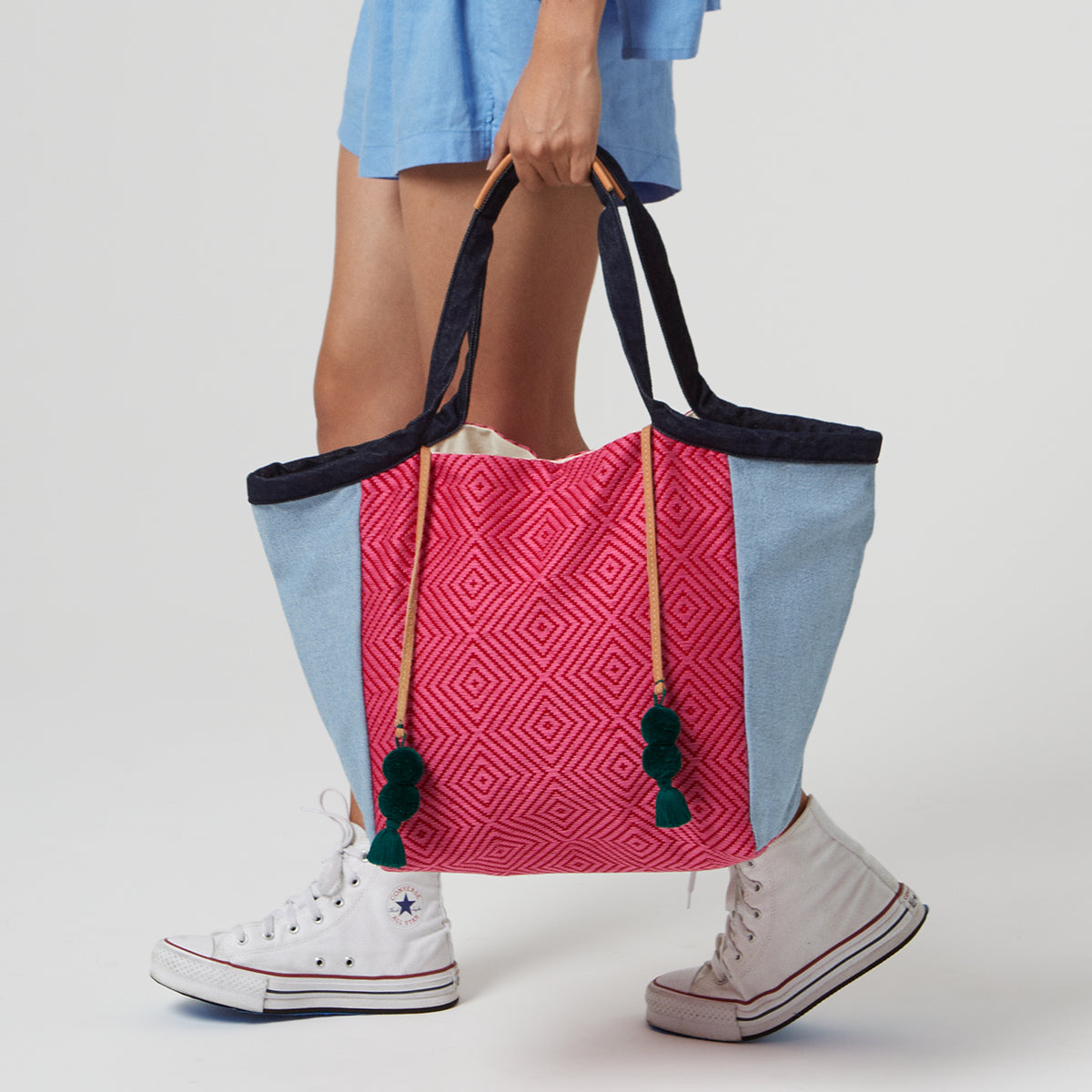 A model holds the hand woven artisan Rosa Tote in Raspberry pattern.