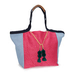 A side view of the hand woven artisan Rosa Tote in Raspberry. The leather cords are tied together.