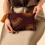 Hand woven artisan Raquel Clutch in Season Sparkle. A model holds the Raquel clutch in her lap. The photo is zoomed in to show the embroidered detailing of the clutch.