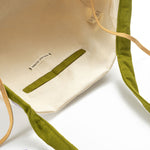 A photo of the interior view of the hand woven artisan Rosa Tote in Woodland Stripes. It has a beige lining and an interior pocket. 