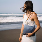 A model wears the unfolded Florentina Clutch-to-Hobo (Ocean Breeze) over her shoulder.