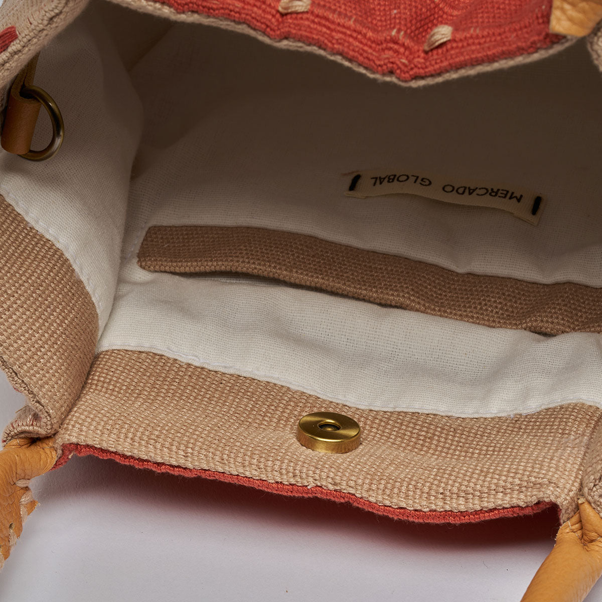 Interior view of the Flora Petite Tote in Desert Sands. It has white cotton lining and a tan hem for the interior pocket. It has a magnetic clasp.