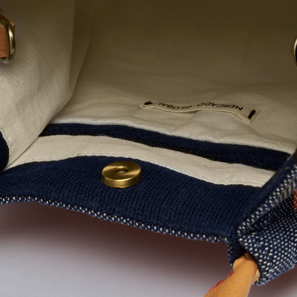 Interior view of the Flora Petite Tote in Blue Canyon. It has white cotton lining and a navy hem for the interior pocket. It has a magnetic clasp.