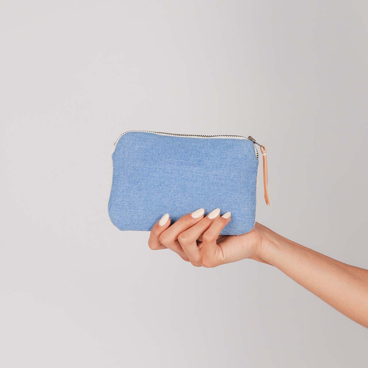 A model holds the back of the hand woven artisan Teresa Wallet in Spring Sherbert. The back has a solid blue color.