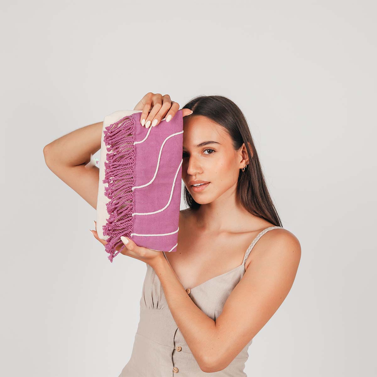 A model holds the hand woven artisan Margarita Clutch in Cosmic Waves, covering one side of her face.