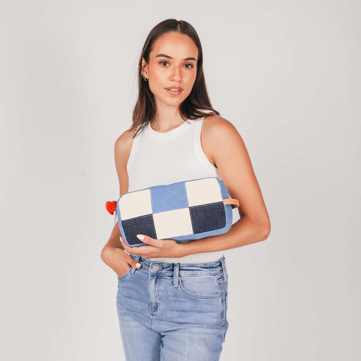 A model holds the hand woven artisan Edna Dopp Kit in 90s Denim on her forearm.