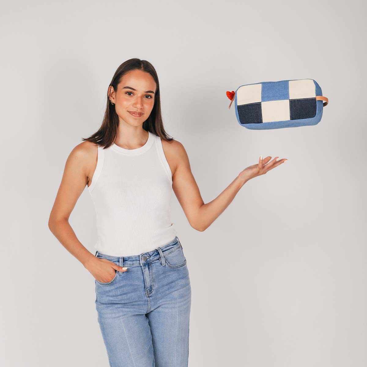 A model poses with the hand woven artisan Edna Dopp Kit in 90s Denim suspended in air. 