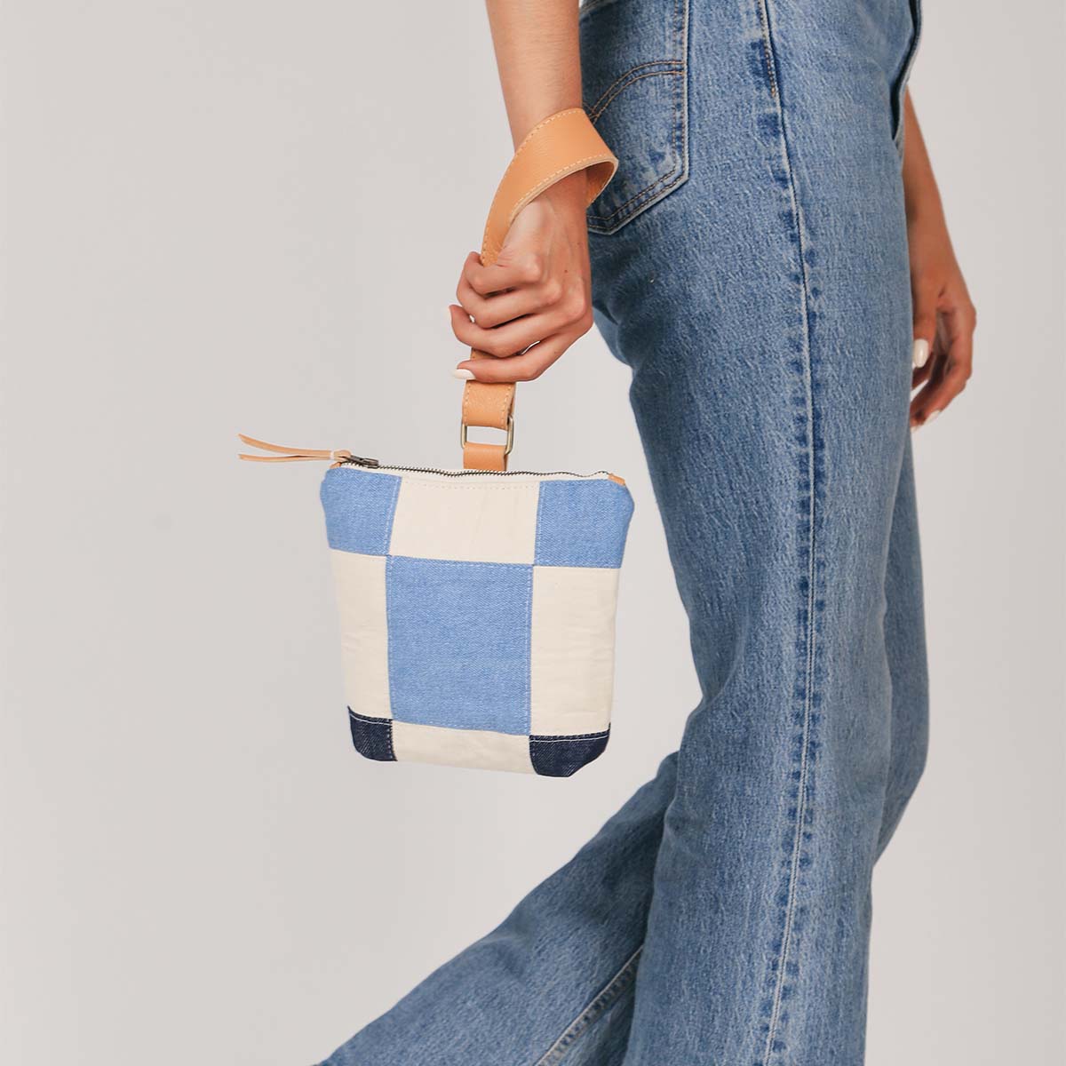 A model wears the hand woven artisan Ofelia Clutch in 90s denim around her wrist. 