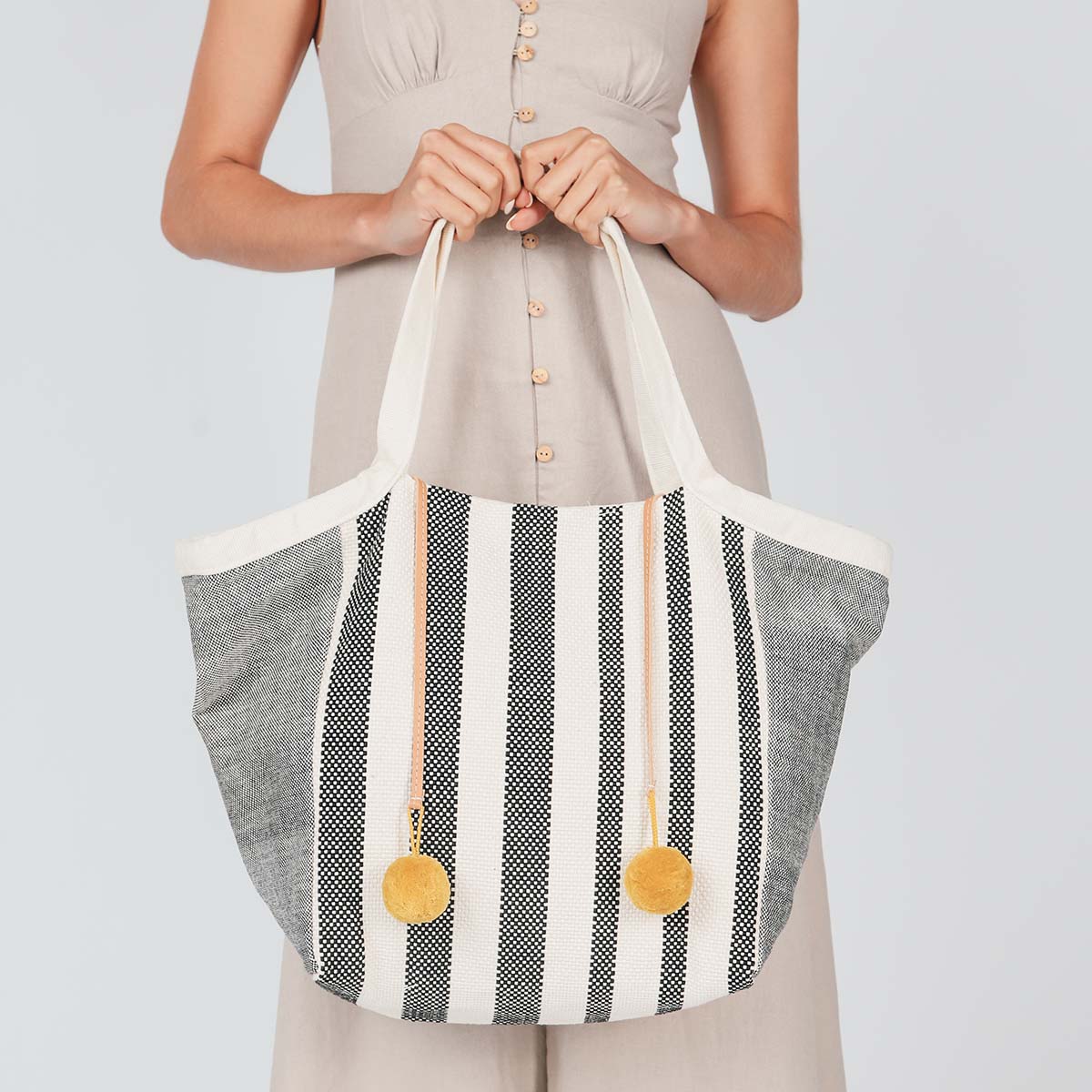 A model holds the hand woven artisan Rosa Tote in a Tourmalline pattern.