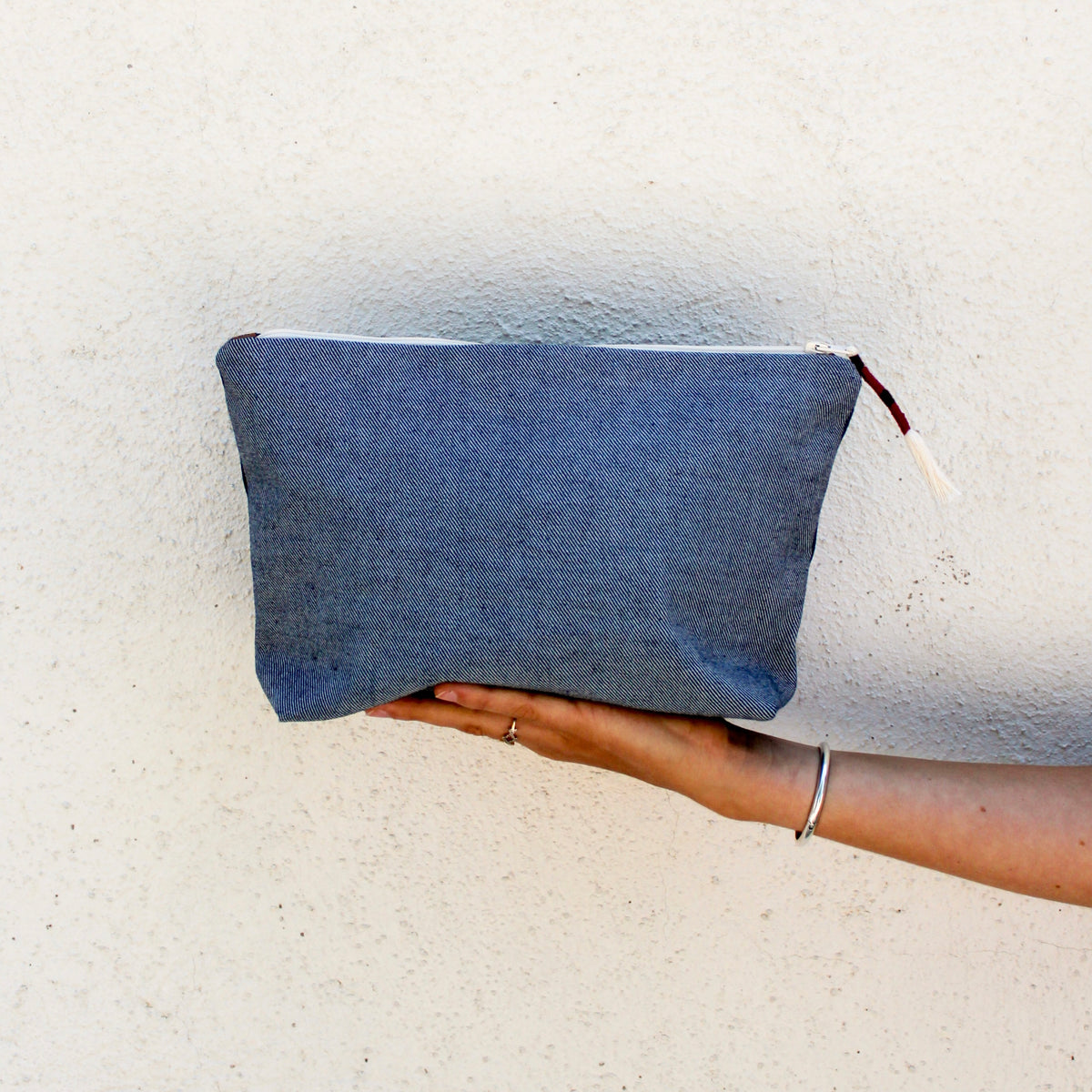 A model holds the backside of the Cristina Pouch in denim.